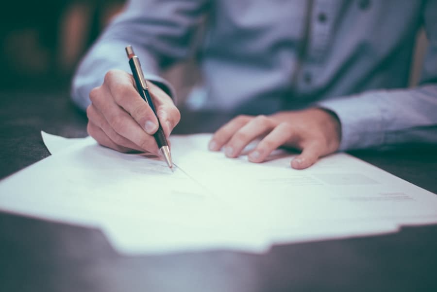 Hand filling out a contract form with a pen